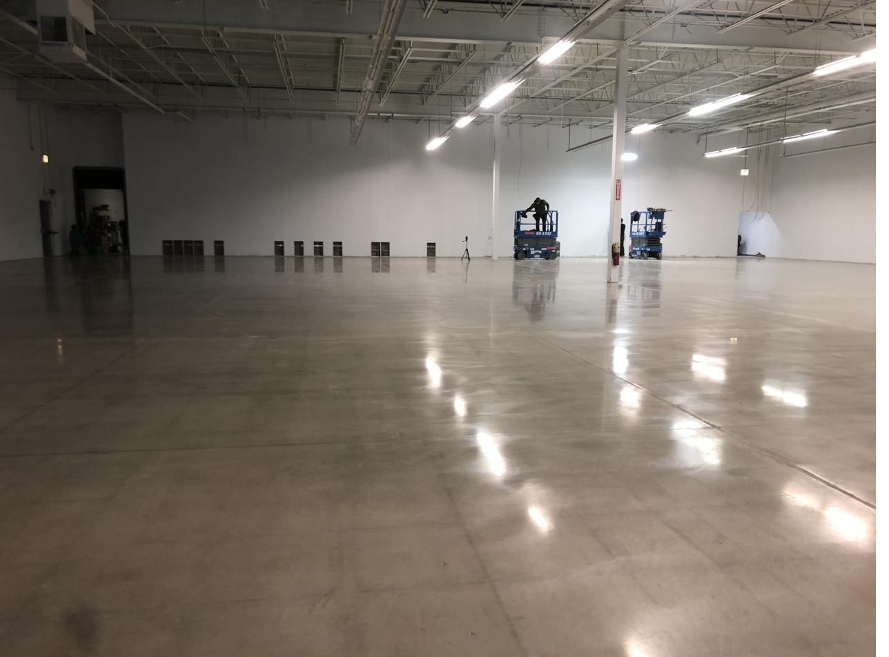 Warehouse floor being polished with scissor lifts on site